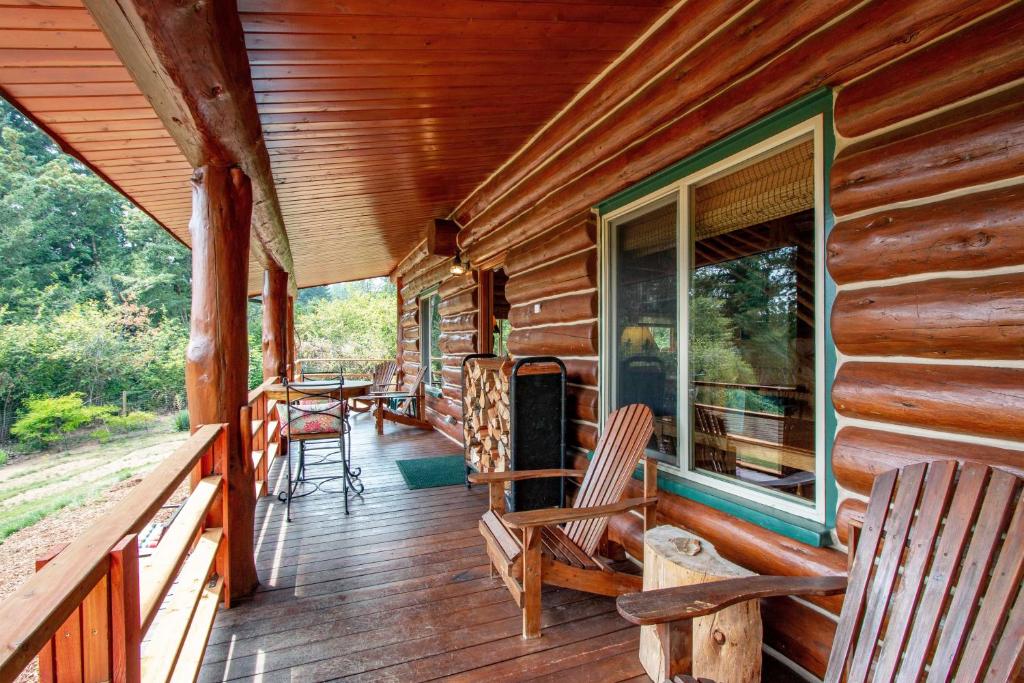 porche de una cabaña de madera con sillas y ventana en The Log Cabin home, en Stevenson