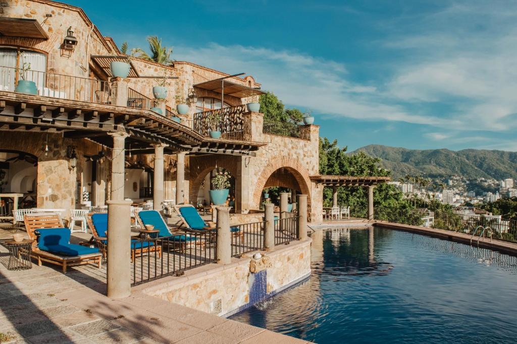 um resort com piscina e cadeiras azuis em Casa Lisa em Acapulco