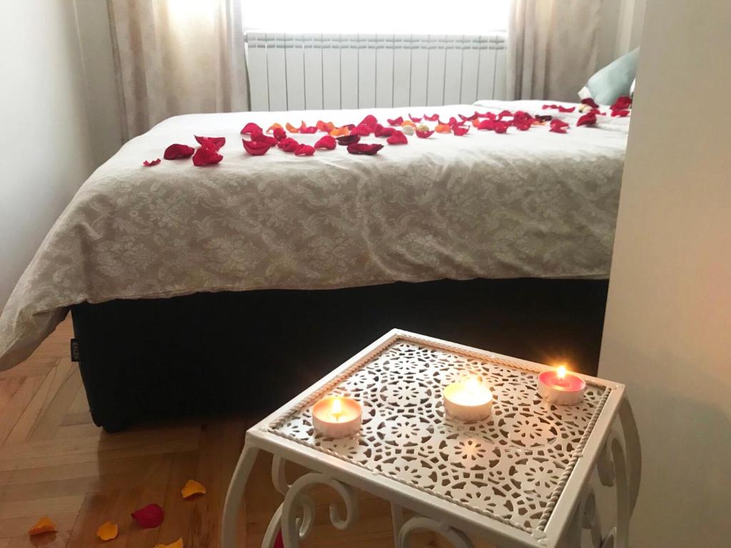 a bed with two candles and roses on it at Apartman Roses in Lukavica