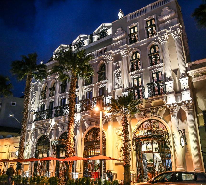 a large building with palm trees in front of it at Hotel Epidamn Boutique & Spa in Durrës