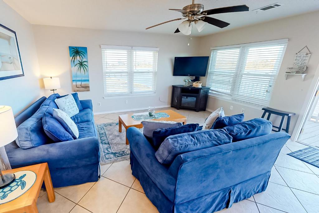 uma sala de estar com dois sofás azuis e uma televisão em The Rusty Pelican em Gulf Shores