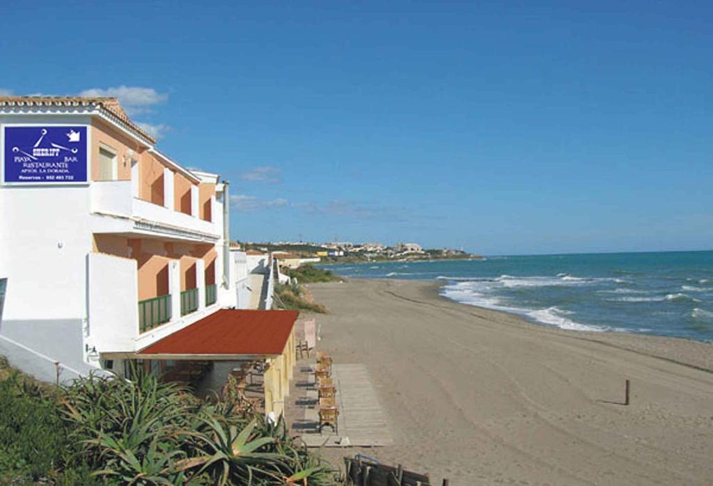 a building on a beach next to the ocean at Apartamentos La Dorada in La Cala de Mijas