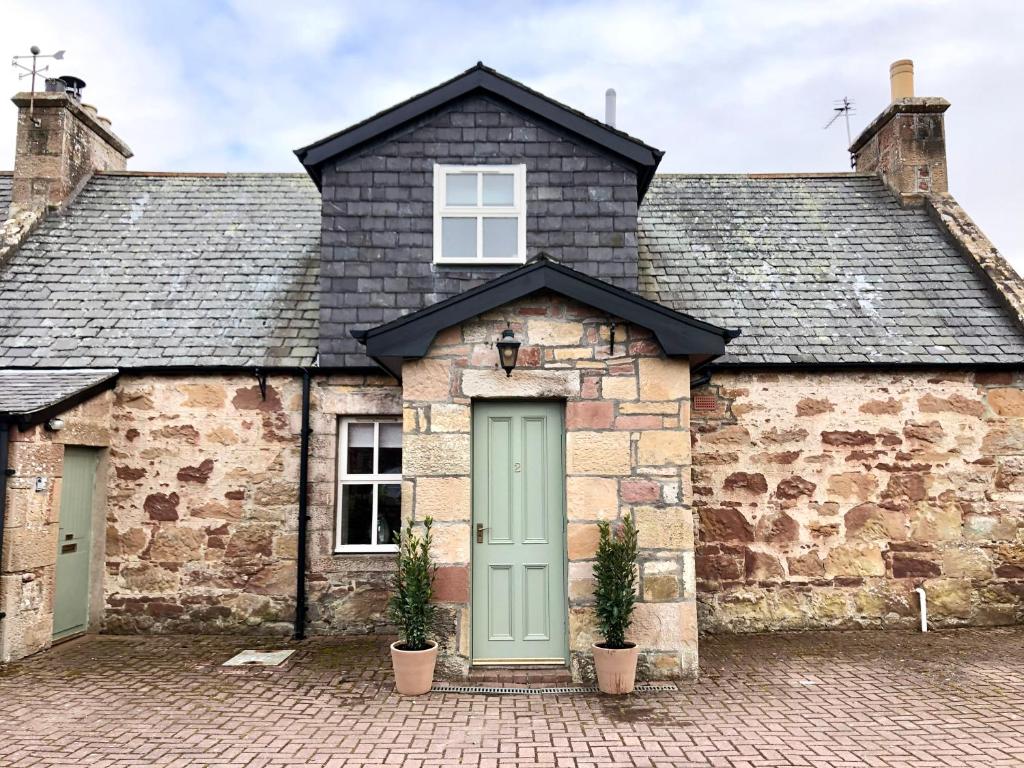 an old stone house with a green door at Glenmuir Cottage in Dornoch