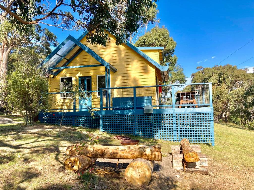 una casa gialla con una recinzione di fronte di Lorne Bush House Cottages & Eco Retreats a Lorne