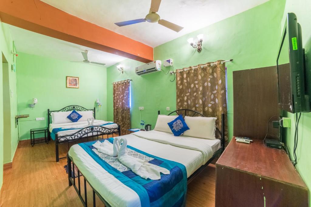 a hotel room with two beds and a tv at Kiara Hotel Goa in Anjuna