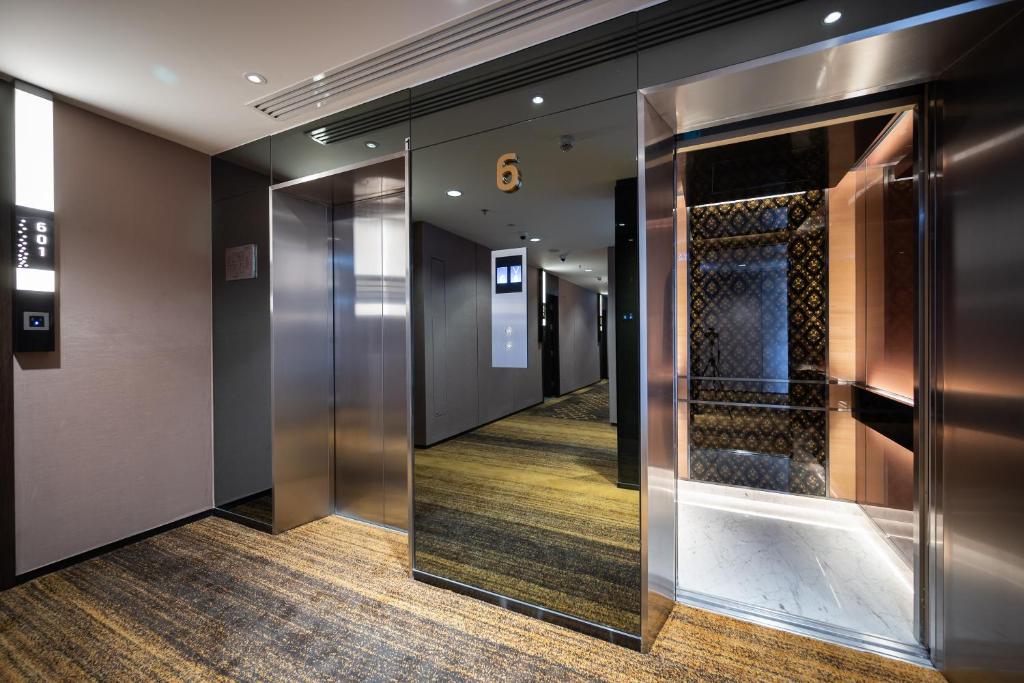 The elevator lobby has mirrored doors, patterned carpet and one brightly decorated lift.