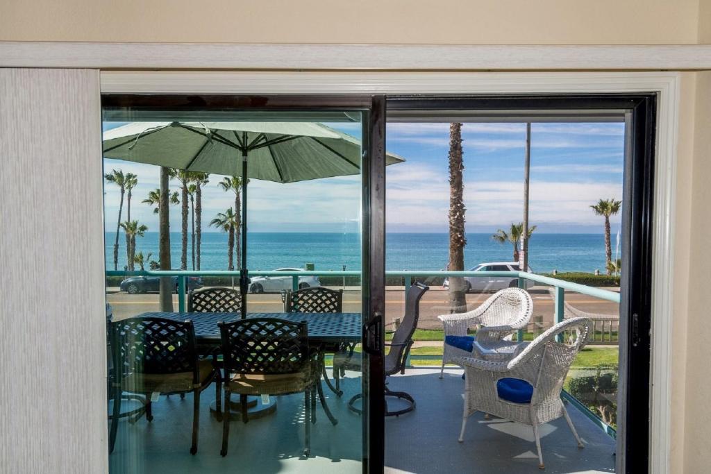 un patio con mesa, sillas y sombrilla en Ocean View with Large Balcony, Air Conditioned, en Oceanside