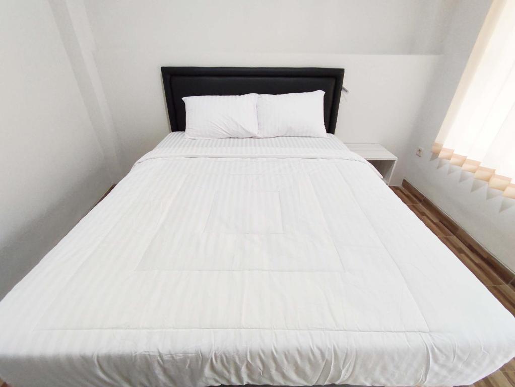 a white bed with a black headboard in a bedroom at Maita Homestay Ringroad Utara Mitra RedDoorz in Kejayan