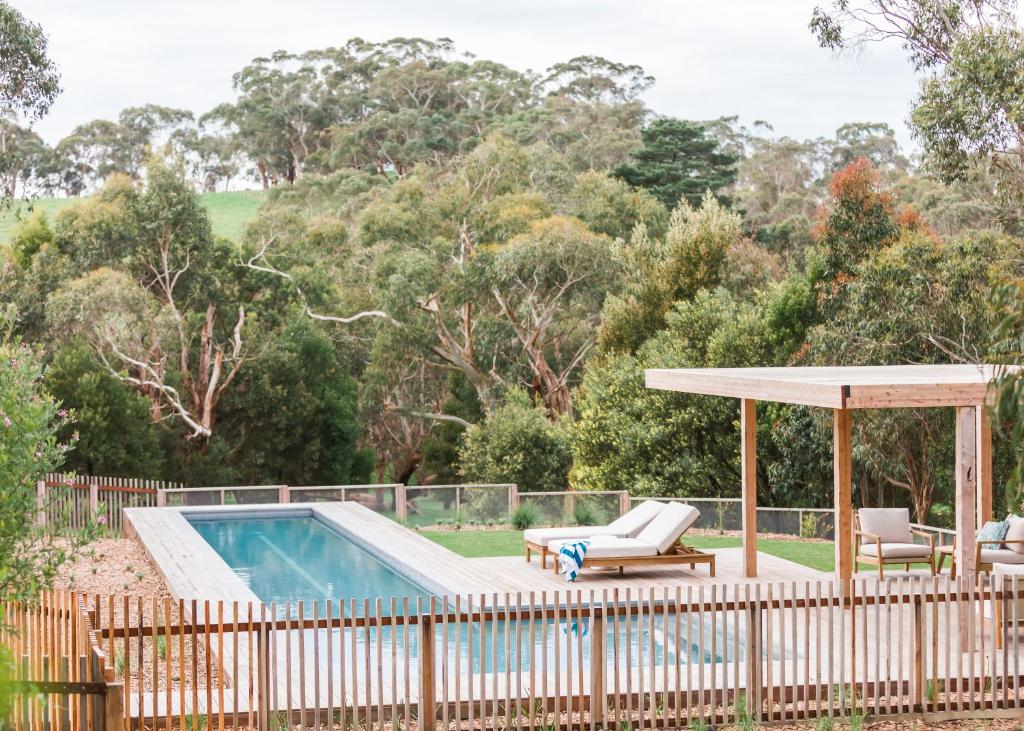 a pool with a pergola and chairs next to a fence at Haven Red Hill in Red Hill