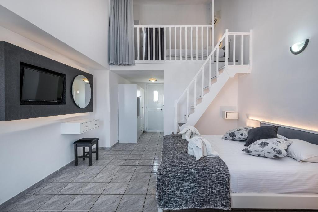 a bedroom with a bed and a tv and stairs at ILIOS K Village Resort in Tigaki