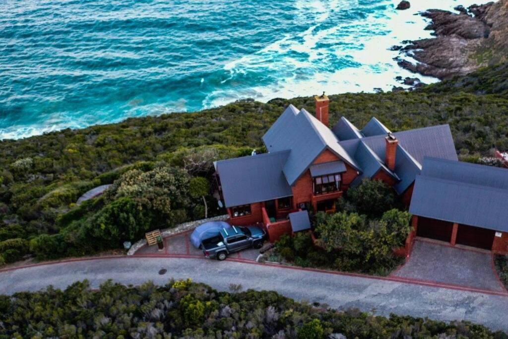 a house with a car parked in front of the ocean at Dolphin View in Herolds Bay