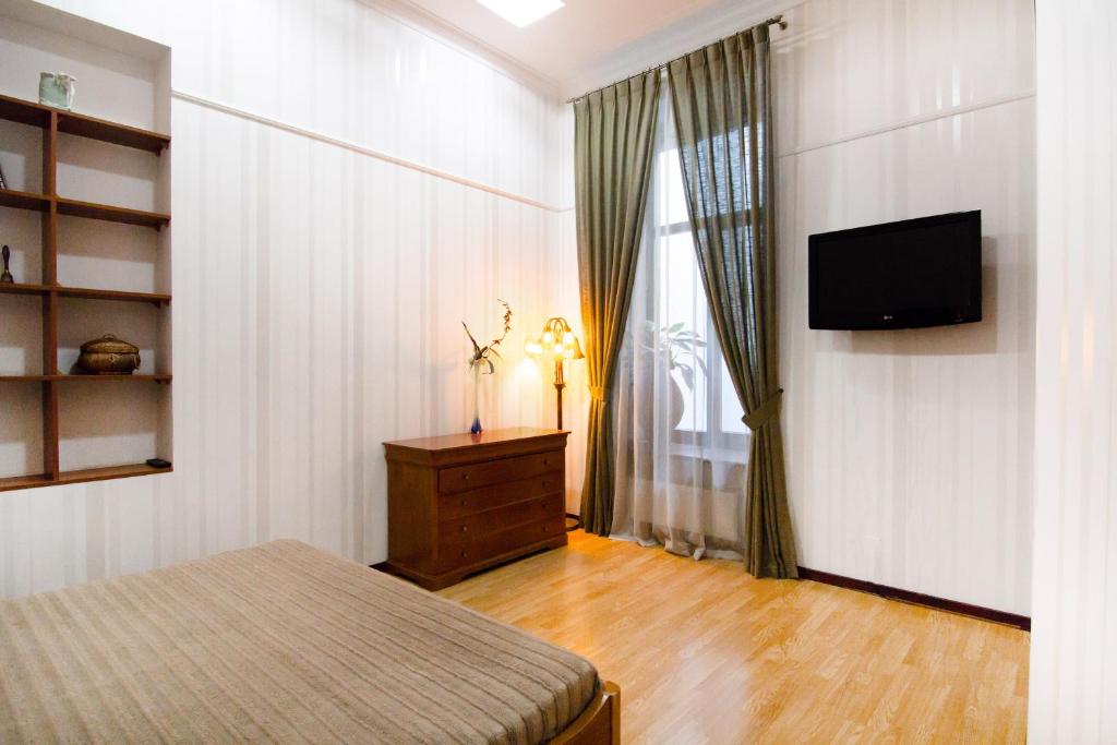 a bedroom with a bed and a television on a wall at Katerynynska Prestige Apartment in Odesa