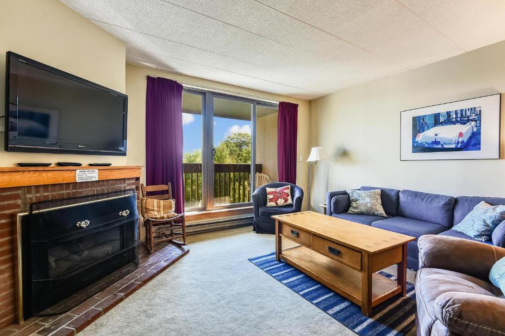 a living room with a couch and a fireplace with a tv at Pinnacle F21 in Killington