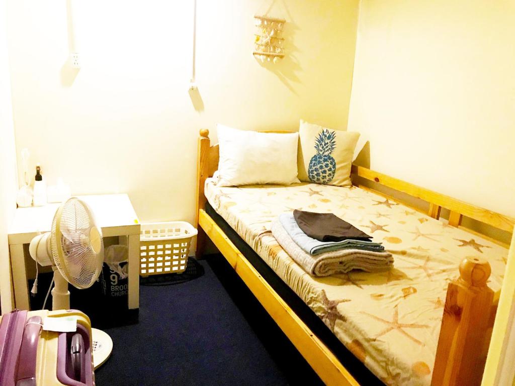 Guesthouse Churayado Ishigakijima في جزيرة إيشيغاكي: غرفة نوم صغيرة بها سرير ومروحة