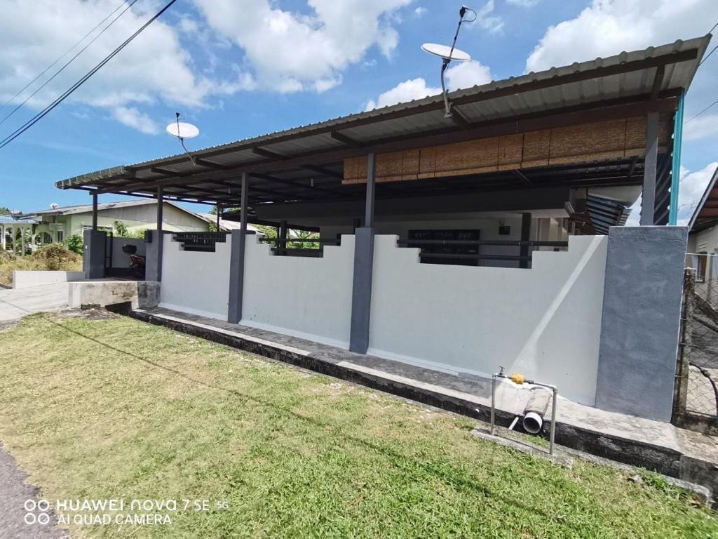 een groot wit gebouw met een dak boven een tuin bij SingLeisure Holiday House in Mersing