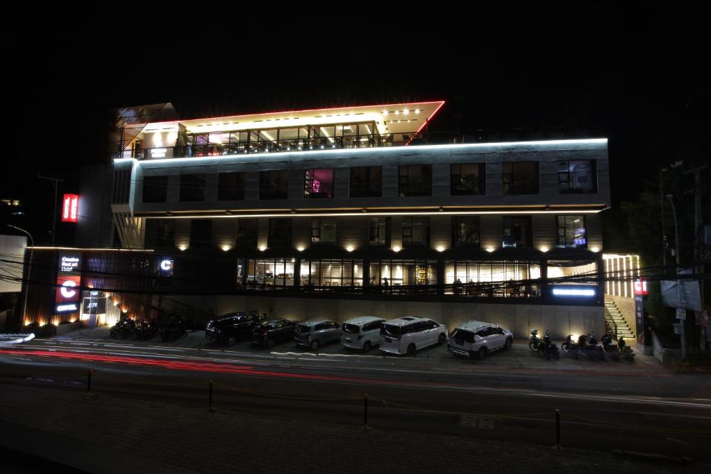um edifício com carros estacionados em frente a ele à noite em Creative Restart Hotel - CARTEL Bandung em Bandung