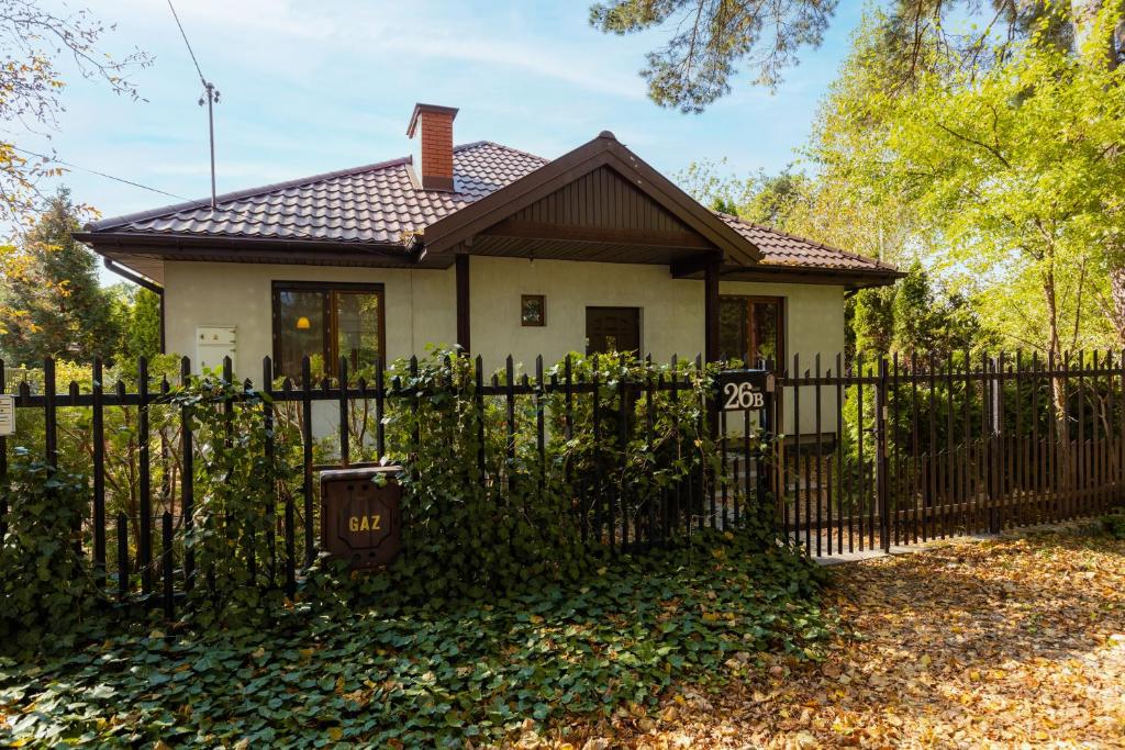 a small white house with a fence and trees at Holiday House Cinema Experience Warsaw Michałowice by Renters in Michałowice