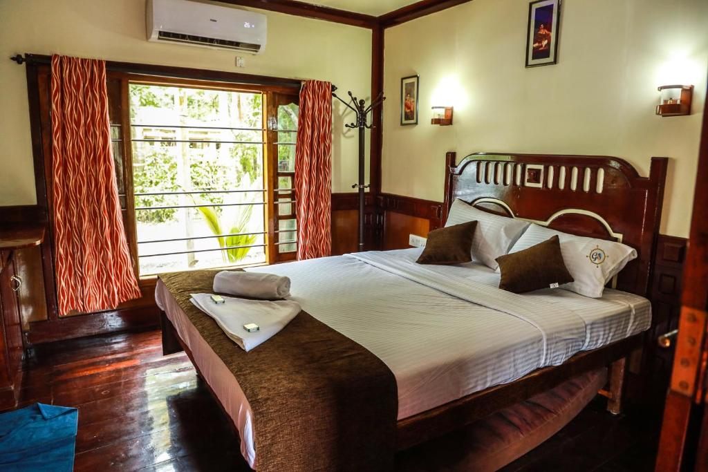 a bedroom with a large bed and a window at Grand Villa Houseboat in Kumarakom