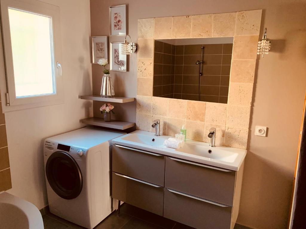 a bathroom with a washing machine and a sink at Nid’Ange in Piolenc
