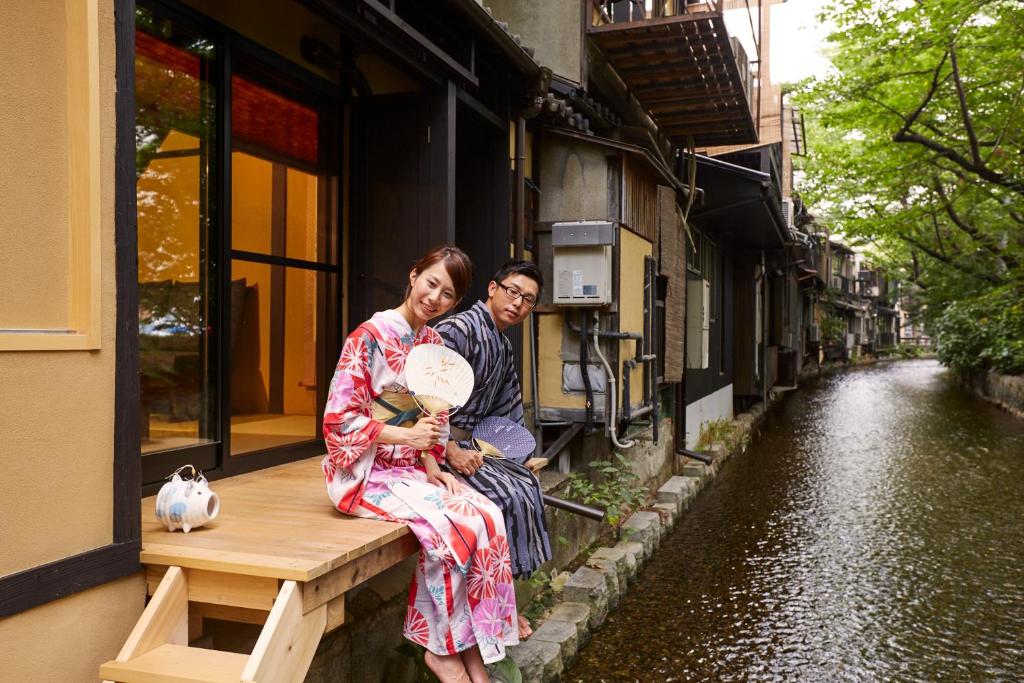 een man en vrouw op een bank naast een kanaal bij Rinn Shijo Takasegawa in Kyoto