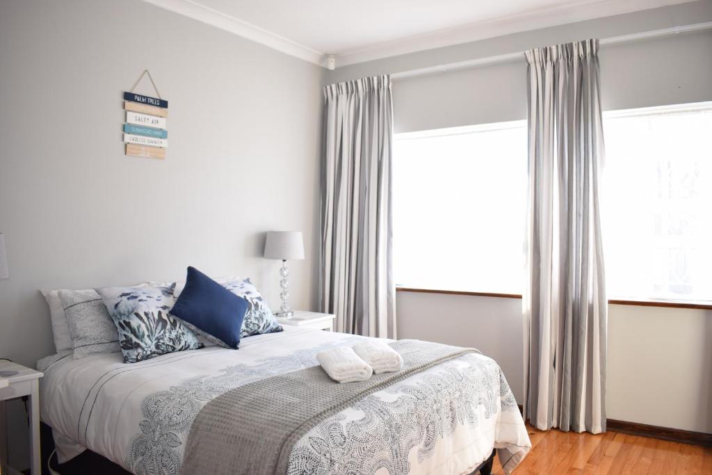 um quarto branco com uma cama com almofadas azuis em Secure Private Flatlet in Newton Park em Port Elizabeth