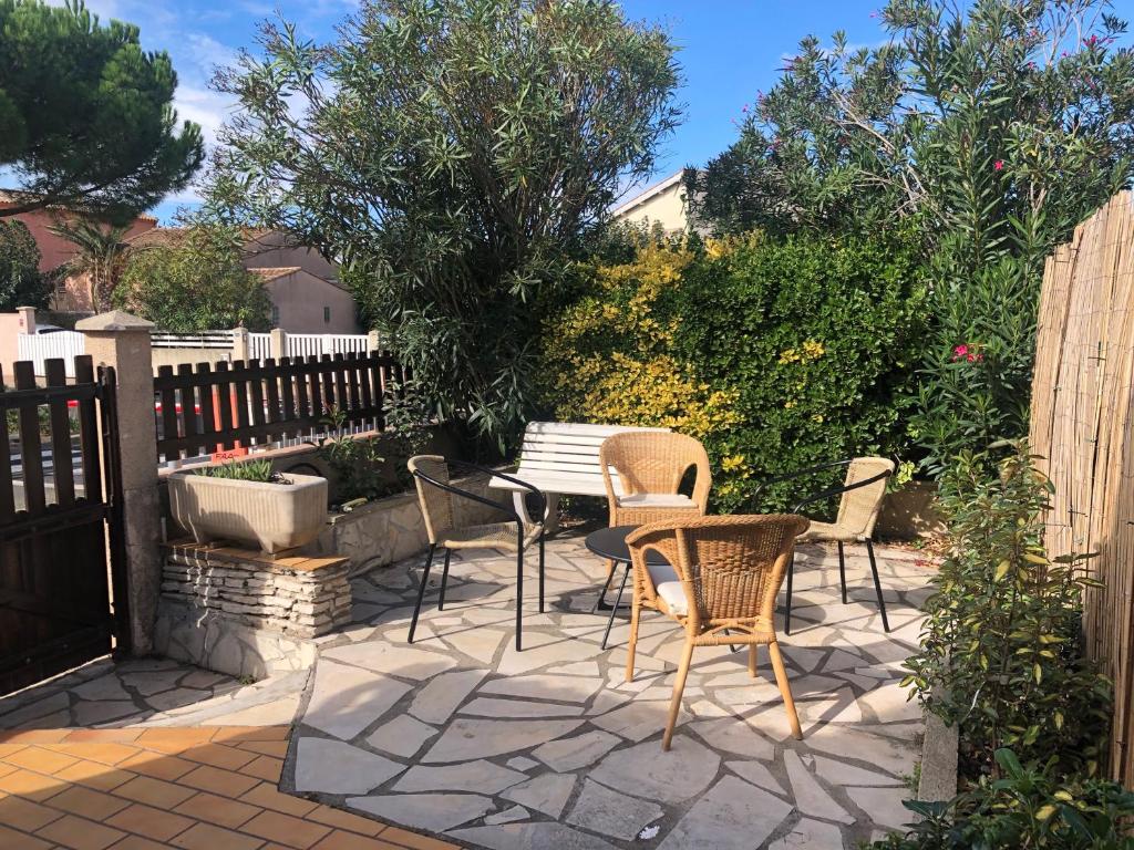 un patio avec des chaises et une table et une clôture dans l'établissement Confort et calme à deux pas des plages de Valras, à Valras-Plage
