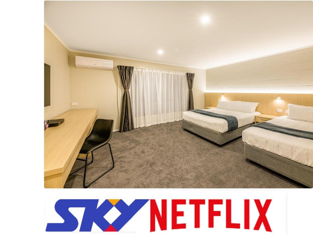 um quarto de hotel com duas camas e uma secretária em Takapuna International Motor Lodge em Auckland