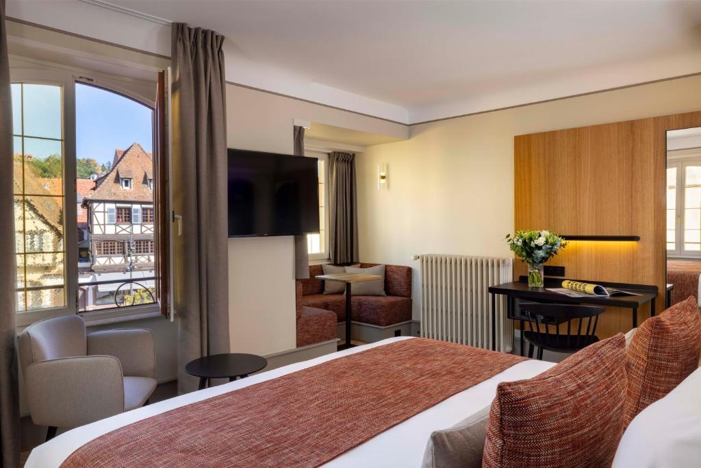 a hotel room with two beds and a television at Hotel La Diligence in Obernai