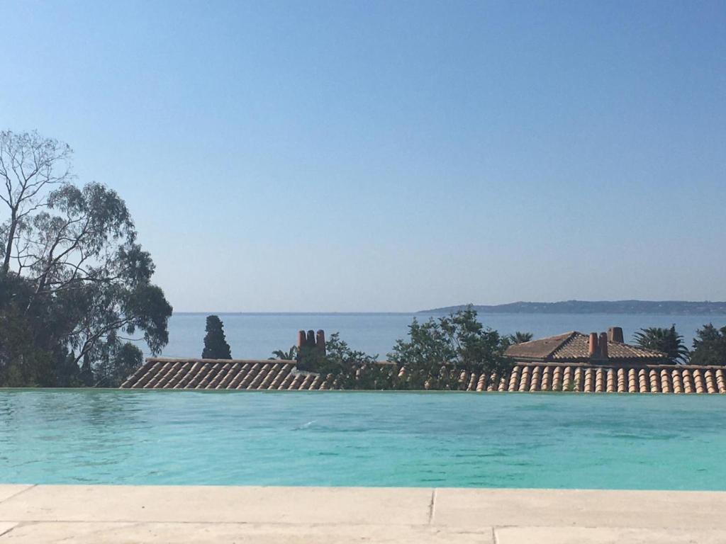 une piscine d'eau bleue avec un bâtiment en arrière-plan dans l'établissement VILLA REVA 3 CHAMBRES, aux Issambres