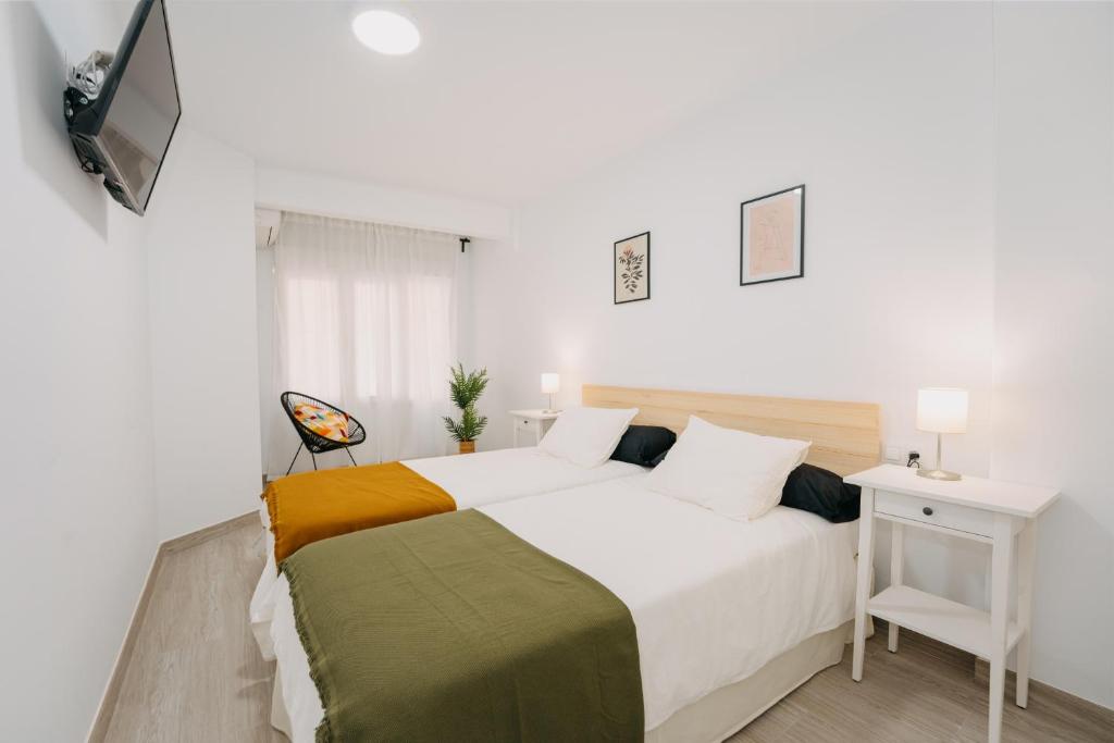 ein weißes Schlafzimmer mit einem großen Bett und einem TV in der Unterkunft Top2Stay Alhóndiga in Málaga