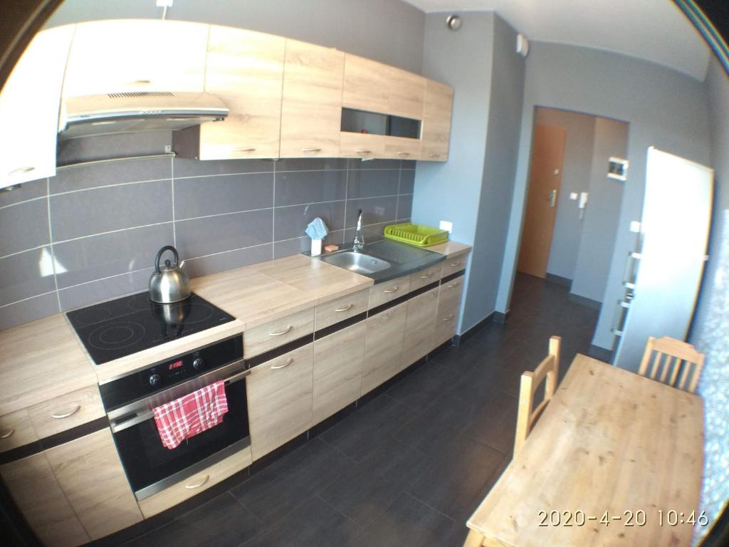 cocina con armarios de madera, fregadero y mesa en 2060 Zwycięstwa 5G - Tanie Pokoje w apartamencie - samodzielne zameldowanie - self check in, en Poznan