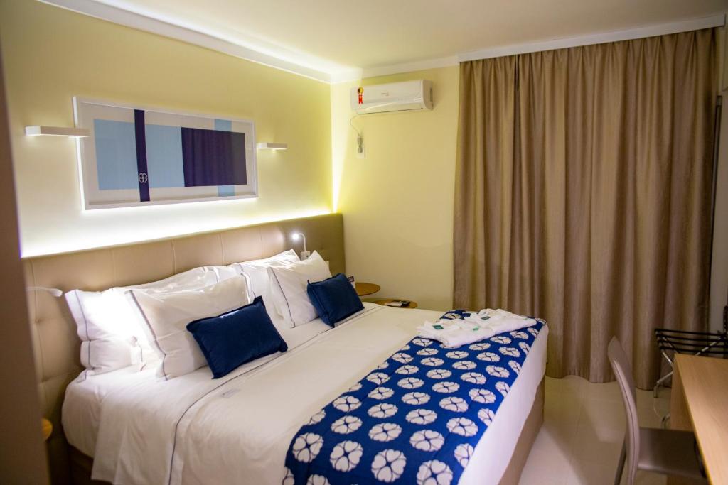 um quarto de hotel com uma cama grande com almofadas azuis em House Inn Hotel - Anashopping em Anápolis