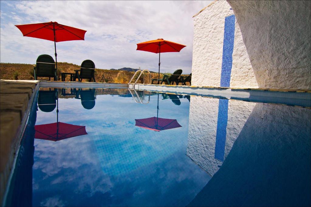 een zwembad met parasols en stoelen en een zwembad bij Cueva Pura Vida in Pulpite