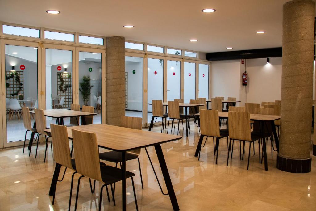 ein Restaurant mit Tischen, Stühlen und Fenstern in der Unterkunft Hotel Alda Orzán in A Coruña