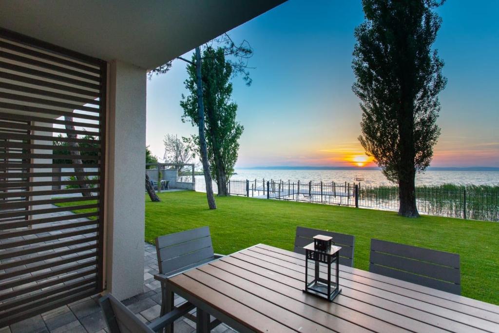 a wooden table and chairs on a patio with a view of the ocean at Beach 101 Villa in Siófok