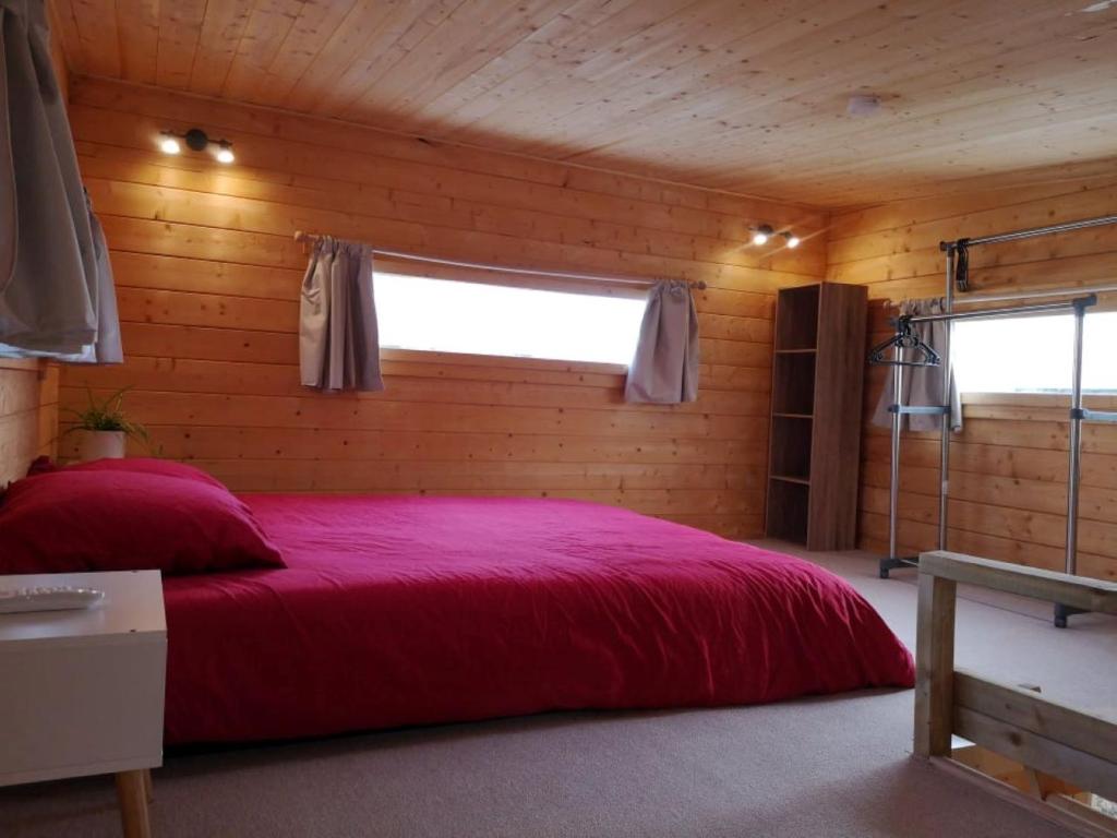 1 dormitorio con 1 cama roja en una habitación de madera en Le Petit Chalet de Nîmes Shantay Youstay en Nimes