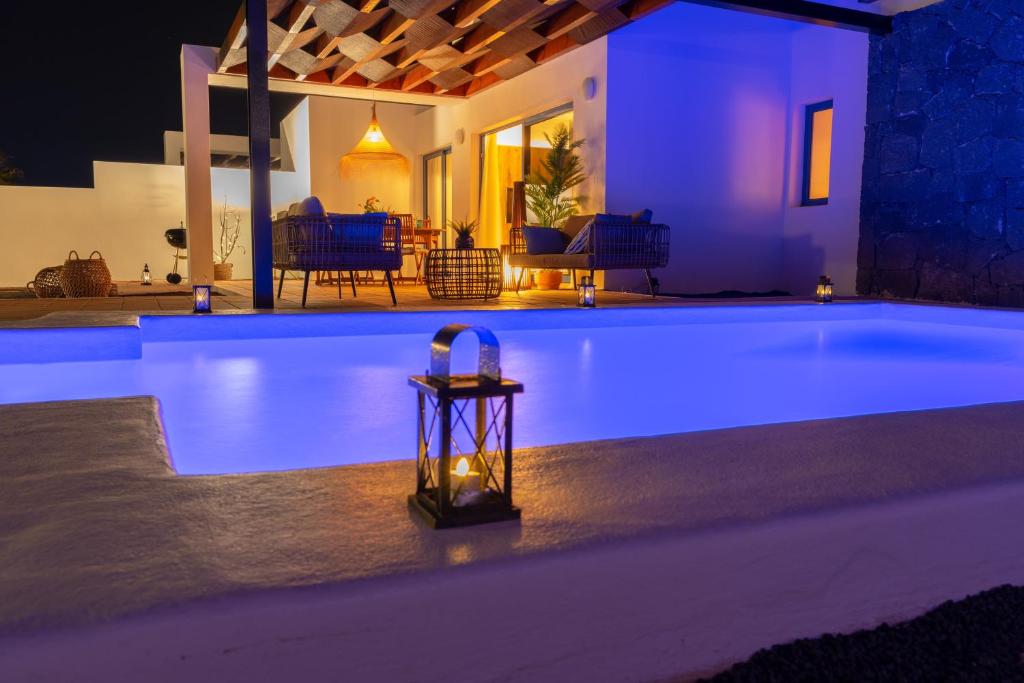 een zwembad verlicht in de nacht met een tafel ernaast bij Villalia Briseida in Playa Blanca