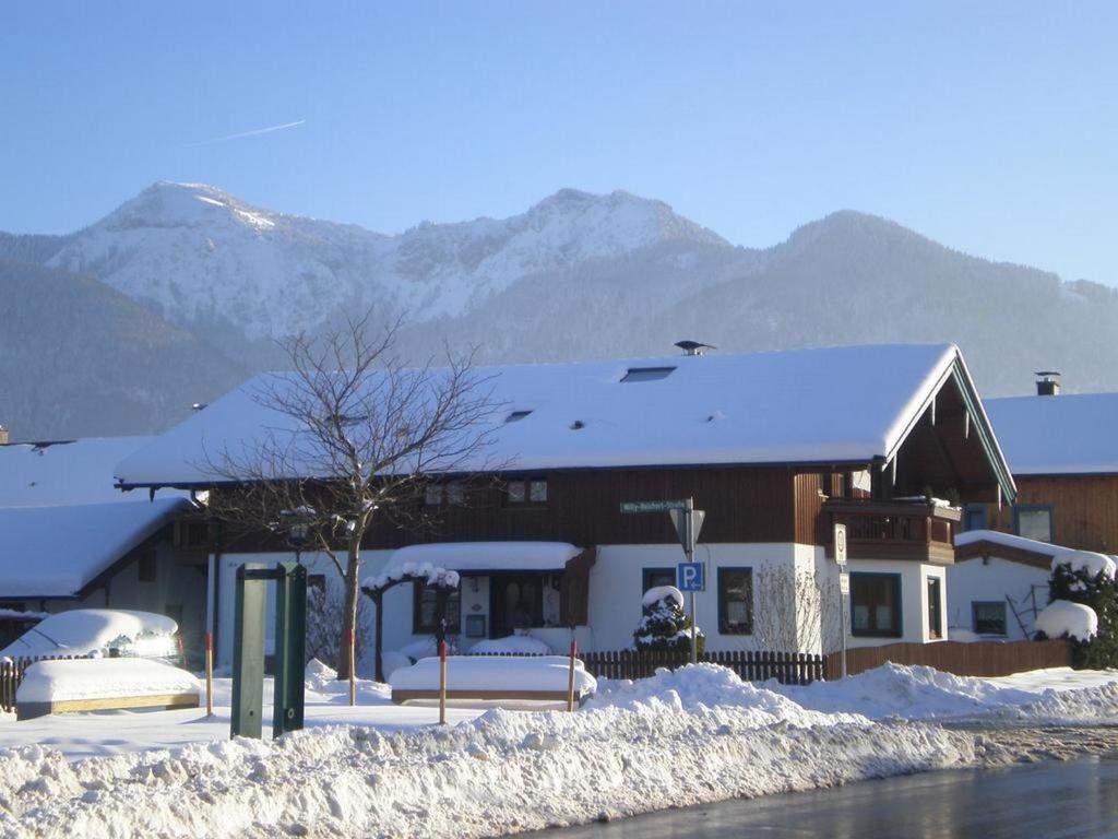 ein schneebedecktes Gebäude mit Bergen im Hintergrund in der Unterkunft Ferienwohnung Kreuz in Grassau