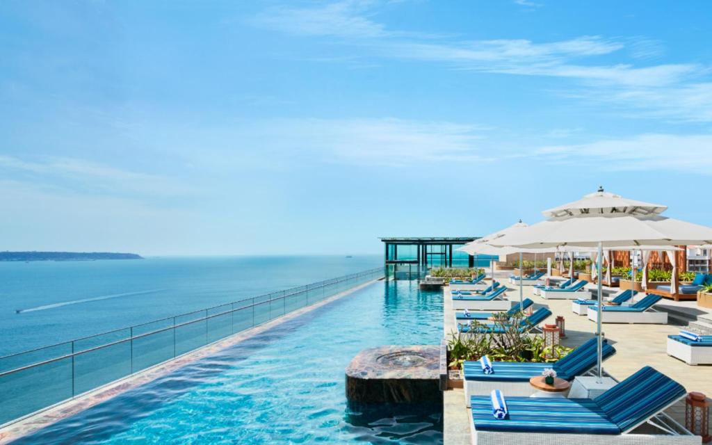 ein Infinity-Pool des Resorts mit Stühlen und einem Sonnenschirm in der Unterkunft Taj Cidade de Goa Horizon, Goa in Panaji