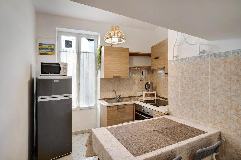 a small kitchen with a table and a refrigerator at Casa via Montà in centro in Sanremo