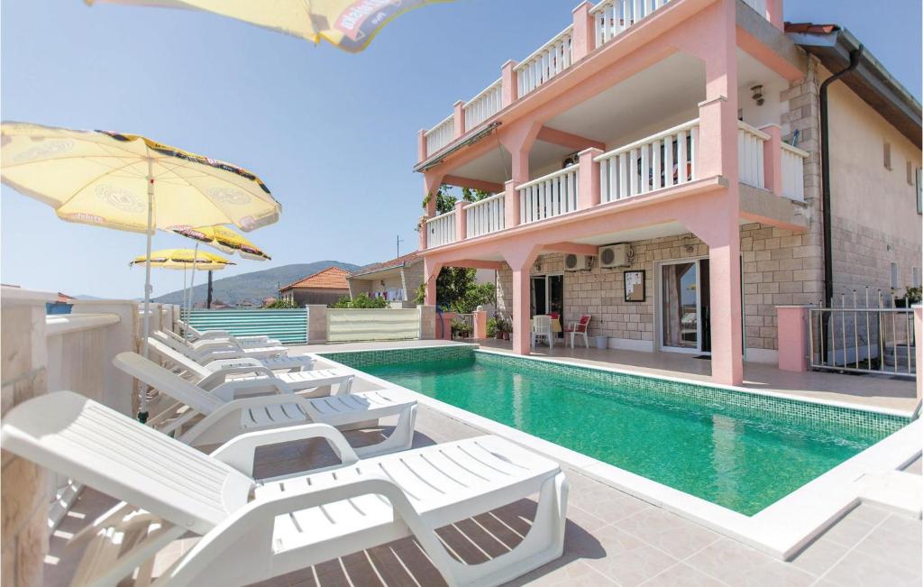 a group of white lounge chairs next to a swimming pool at Nice Home In Trogir With 5 Bedrooms, Outdoor Swimming Pool And Heated Swimming Pool in Trogir