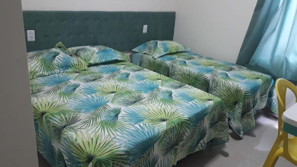 a bedroom with a bed with a green and blue comforter at Santorini Hotel in Santarém