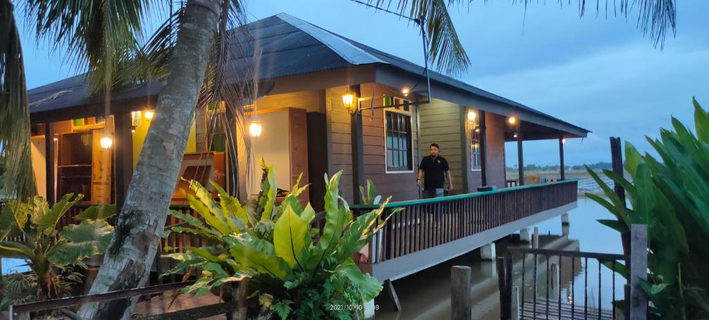 a man standing on the porch of a house at Bungalow Mat Hj Limah in Alor Setar