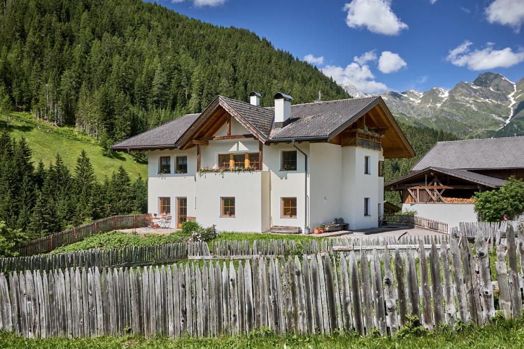 una casa blanca detrás de una valla de madera en Jaufenspitze Blasighof en Racines