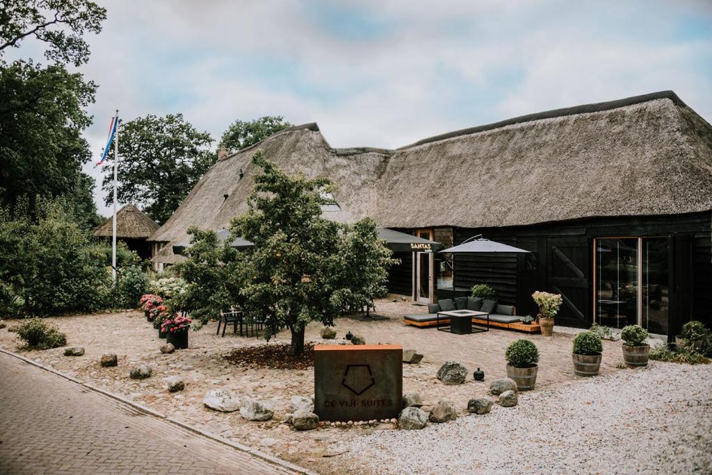 een groot gebouw met een boom ervoor bij De Vijf Suites in Elp