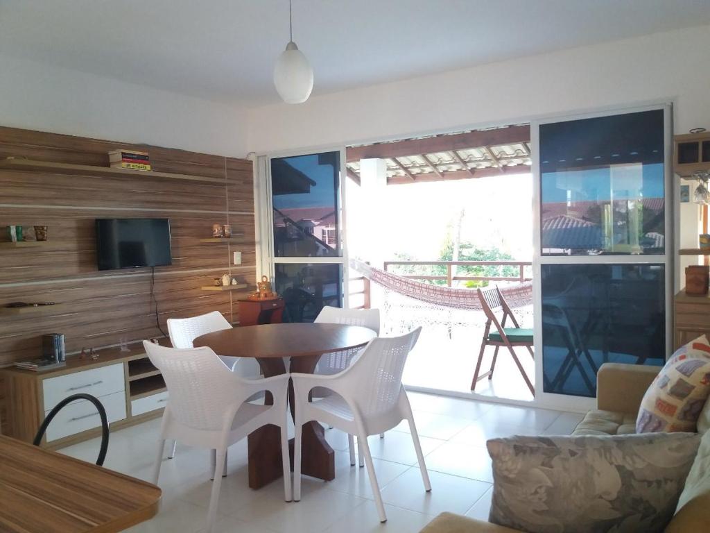 een woonkamer met een tafel en stoelen bij Apartamento Reserva Imbassaí quarto e sala 68m² in Mata de Sao Joao