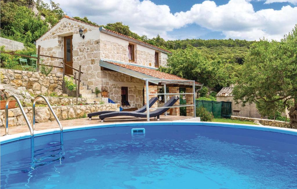 a house with a swimming pool in front of a house at 2 Bedroom Awesome Home In Supetarska Draga in Supetarska Draga
