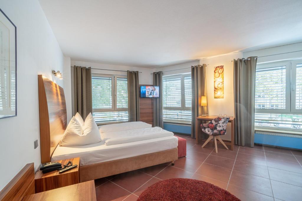 a bedroom with a bed in a room with windows at Hotel Schottenhof in Mainz