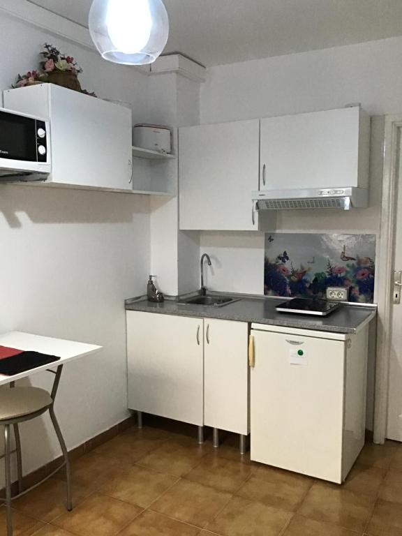 a kitchen with white cabinets and a sink and a table at Apartamentos Playamar in La Playa Calera