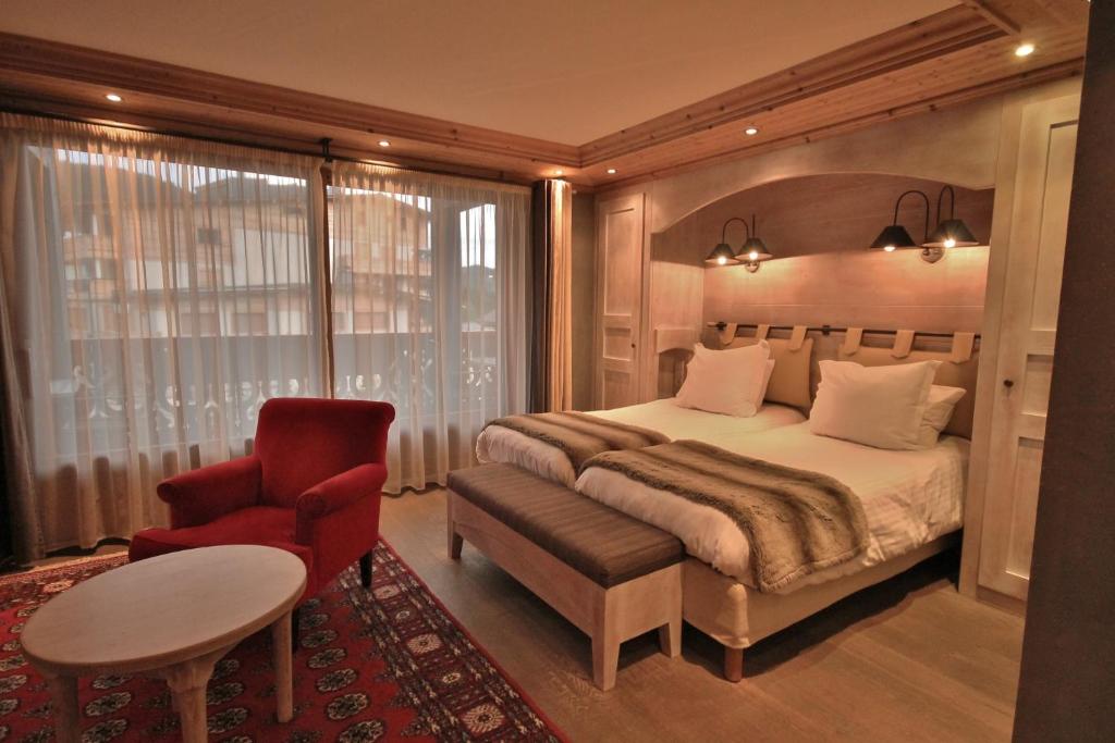 a bedroom with a bed and a red chair at Hôtel Alpina &amp; SPA in Les Gets